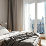A Comfortable Bedroom Scene**

A bright and airy bedroom in a modern Russian apartment, featuring a queen-size bed with a plump duvet and several pillows. The bedding is made of natural linen in neutral tones (cream, light gray). Sunlight streams through sheer curtains. A bedside table holds a lamp and a few books. Focus on creating a sense of coziness and relaxation. Safe for work, appropriate content, fully clothed (no people in the image), professional, modest, family-friendly, perfect lighting, realistic textures, high quality.

**